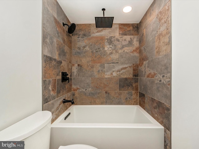 bathroom with toilet and tiled shower / bath