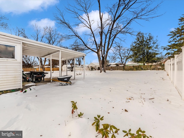 snowy yard featuring a carport