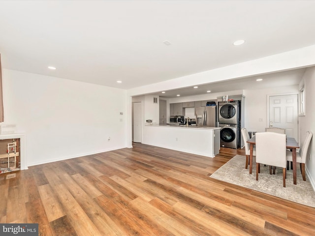 living room featuring sink, stacked washer / drying machine, and light wood-type flooring