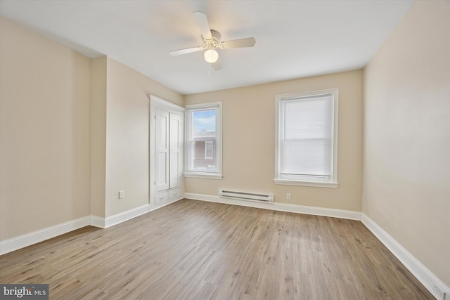 empty room featuring baseboards, wood finished floors, a baseboard heating unit, and ceiling fan