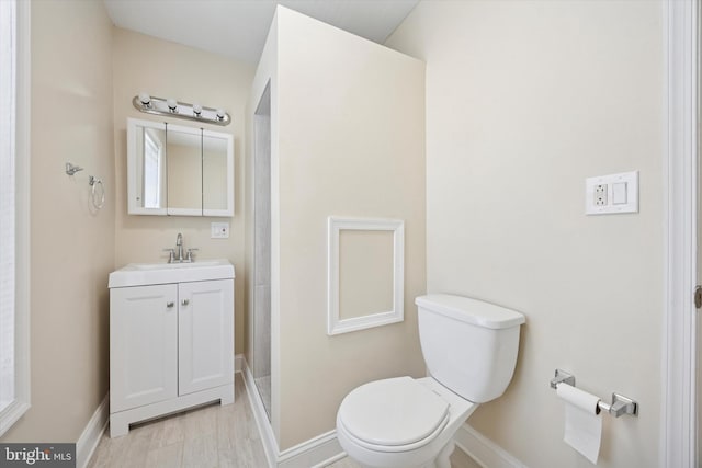 bathroom featuring toilet, vanity, and baseboards