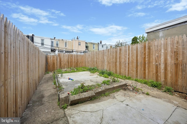 view of yard featuring a fenced backyard, a residential view, a vegetable garden, and a patio area