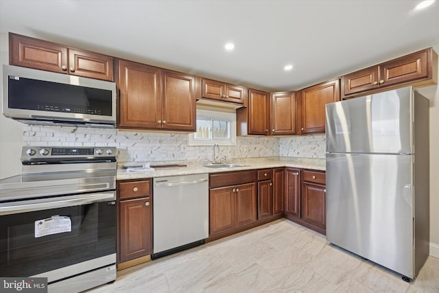 kitchen featuring light stone countertops, stainless steel appliances, backsplash, and a sink