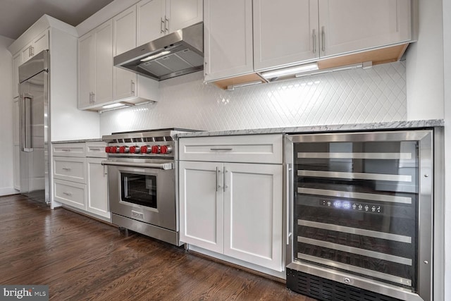 kitchen featuring wine cooler, under cabinet range hood, white cabinetry, high quality appliances, and dark wood-style floors