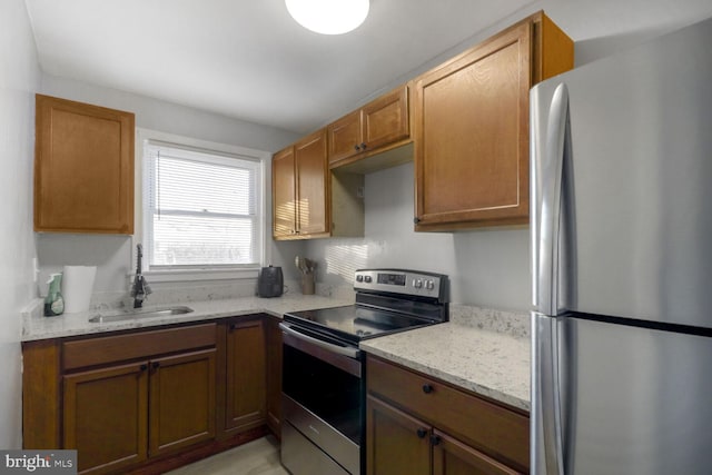 kitchen with appliances with stainless steel finishes, sink, and light stone counters