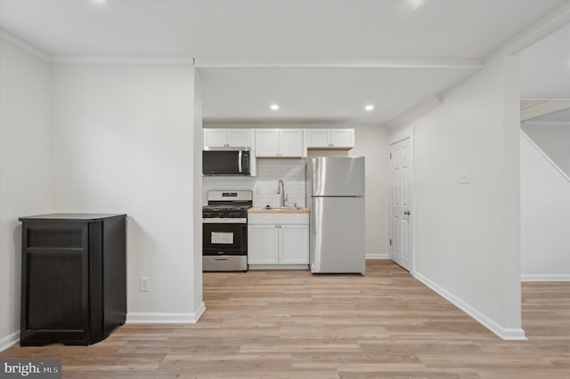 kitchen featuring white cabinets, sink, light wood-type flooring, tasteful backsplash, and stainless steel appliances