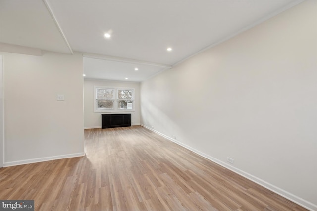 unfurnished living room featuring ornamental molding and light wood-type flooring