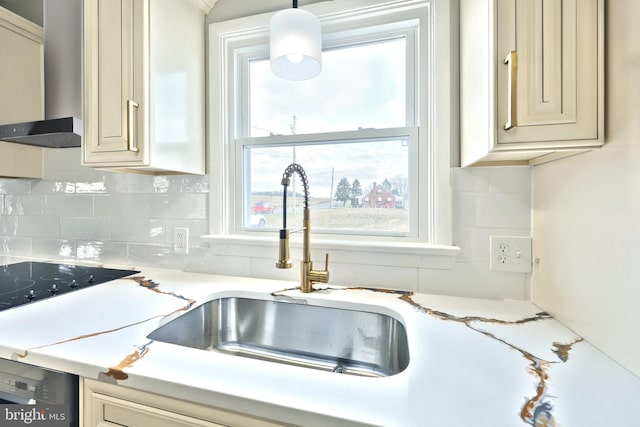 kitchen featuring tasteful backsplash, dishwashing machine, sink, decorative light fixtures, and cream cabinetry