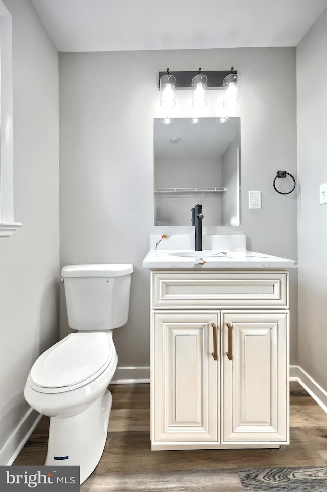 bathroom featuring vanity, wood-type flooring, and toilet