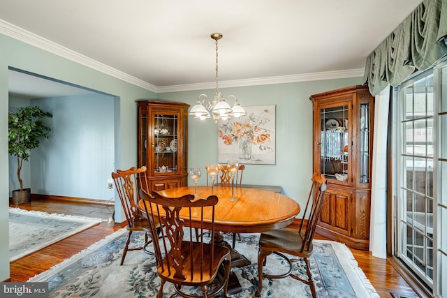 dining space featuring hardwood / wood-style floors, crown molding, and an inviting chandelier