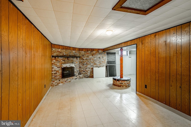 unfurnished living room featuring wood walls and a fireplace