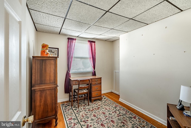 home office with hardwood / wood-style floors and a paneled ceiling