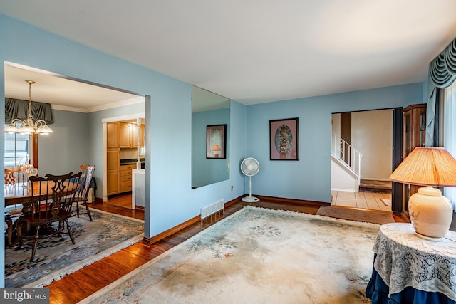 interior space featuring hardwood / wood-style flooring, ornamental molding, and an inviting chandelier