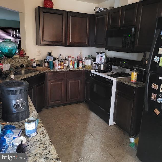 kitchen with black appliances, light stone countertops, and dark brown cabinetry