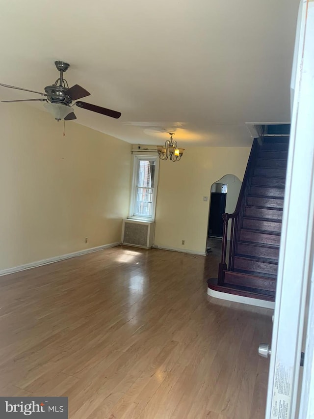 unfurnished living room featuring hardwood / wood-style flooring and ceiling fan with notable chandelier