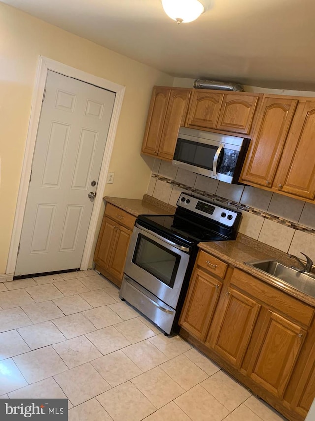 kitchen with appliances with stainless steel finishes, sink, and backsplash