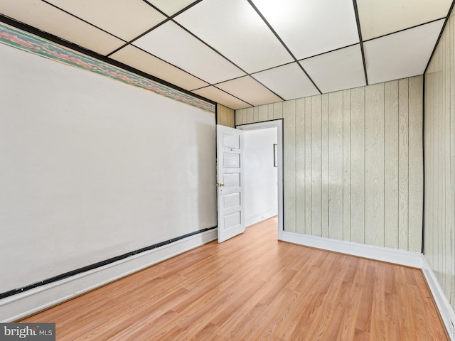 home theater featuring wooden walls, a baseboard radiator, a drop ceiling, and light hardwood / wood-style floors