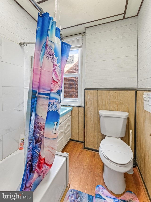 bathroom with toilet, hardwood / wood-style floors, shower / tub combo with curtain, and wooden walls