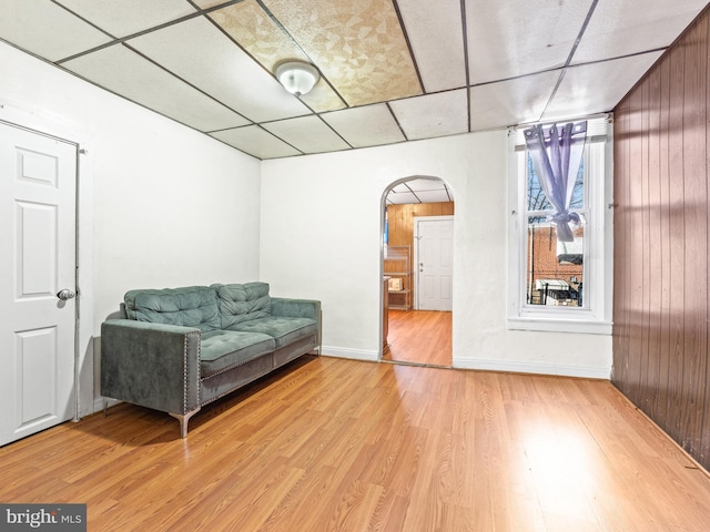 living area with wood walls, a drop ceiling, and light hardwood / wood-style floors