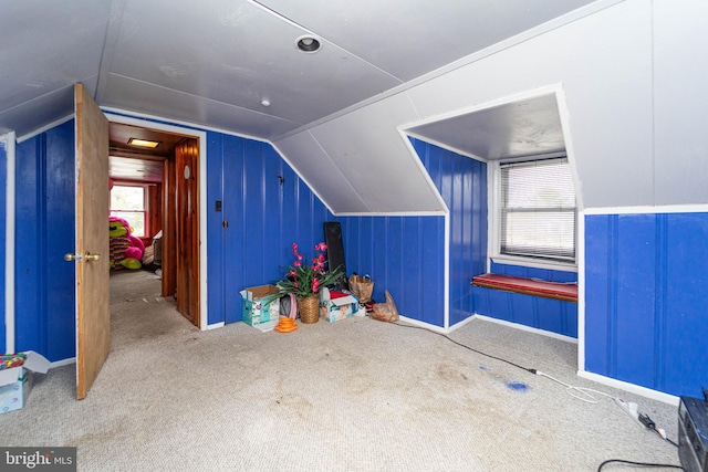 additional living space with carpet flooring, a healthy amount of sunlight, and lofted ceiling