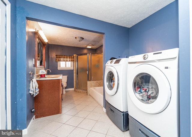 laundry area with washer and dryer, light tile patterned floors, a textured ceiling, and sink