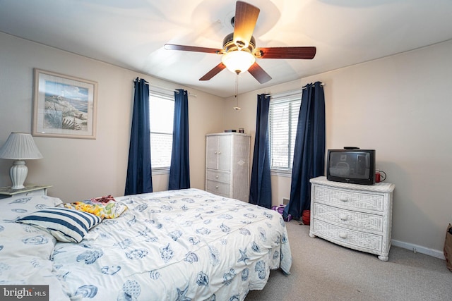 carpeted bedroom featuring multiple windows and ceiling fan