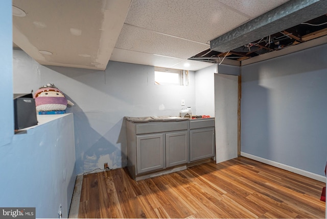 basement with wood-type flooring and a paneled ceiling