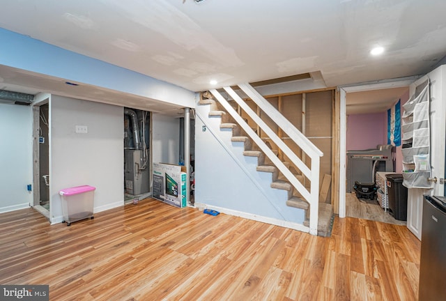 basement featuring light wood-type flooring and heating unit