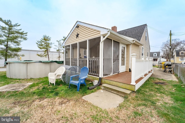 rear view of house featuring a sunroom and a pool side deck