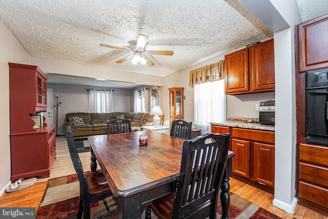 dining room with a textured ceiling, light hardwood / wood-style flooring, and ceiling fan