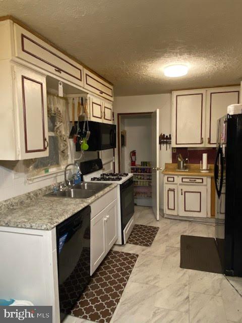 kitchen featuring sink, black appliances, and a textured ceiling