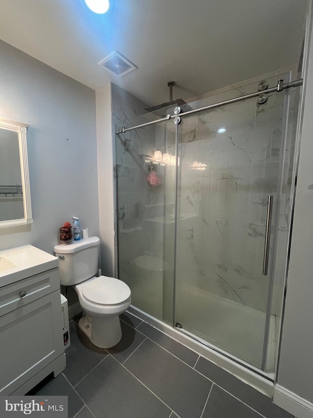 bathroom featuring tile patterned flooring, vanity, toilet, and a shower with shower door