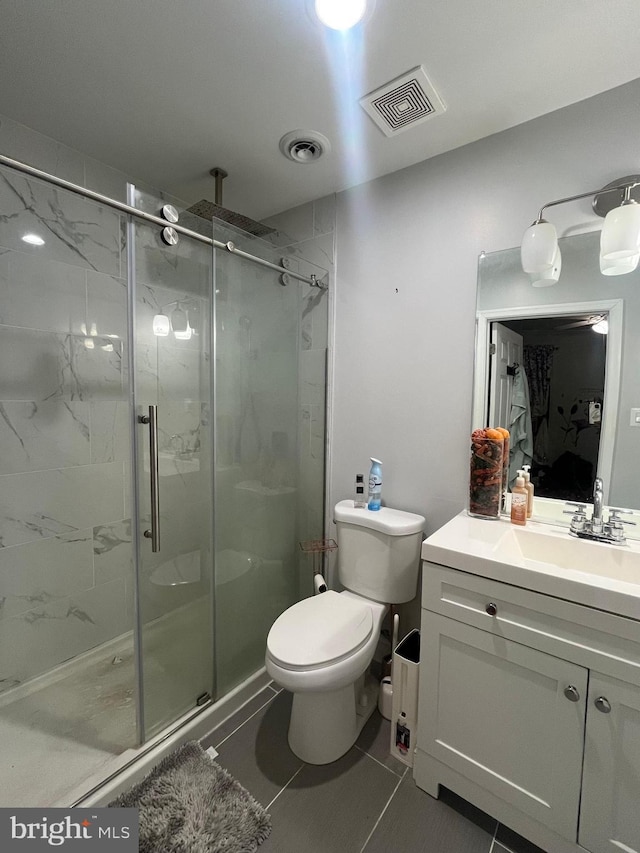 bathroom with tile patterned flooring, vanity, toilet, and a shower with door