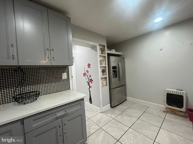 kitchen with decorative backsplash, stainless steel fridge, gray cabinetry, heating unit, and light tile patterned floors