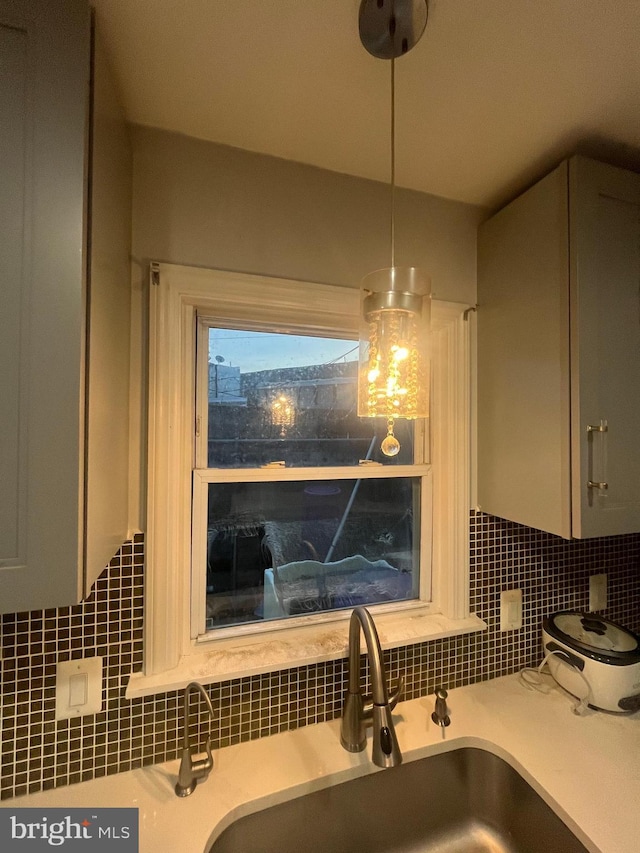 details featuring pendant lighting, decorative backsplash, and sink