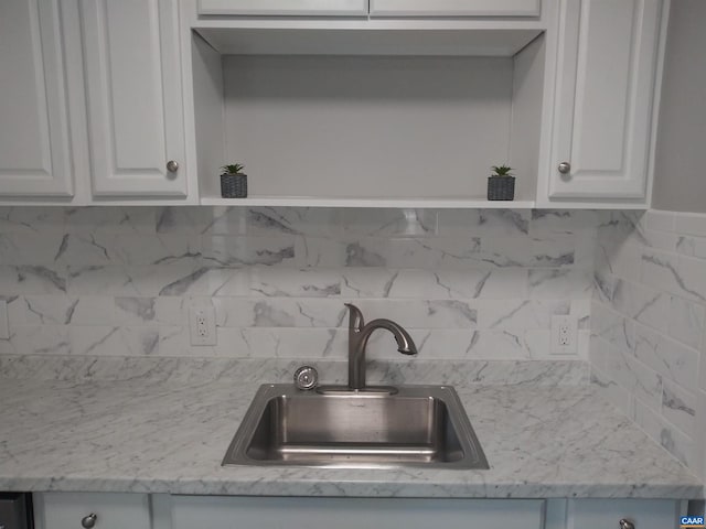 kitchen featuring tasteful backsplash, white cabinetry, and sink