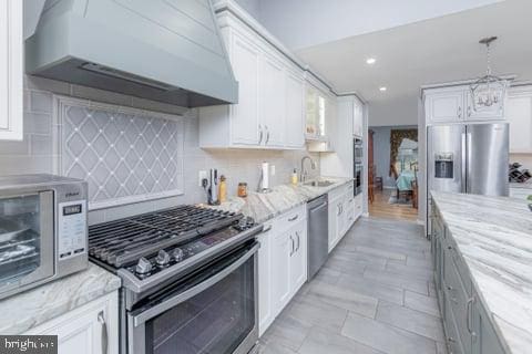 kitchen with white cabinets, stainless steel appliances, and wall chimney exhaust hood