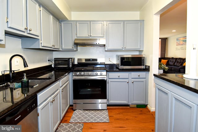 kitchen featuring gray cabinets, sink, stainless steel appliances, and dark stone counters