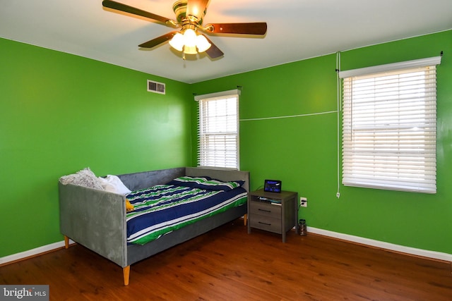 bedroom featuring ceiling fan, dark hardwood / wood-style floors, and multiple windows