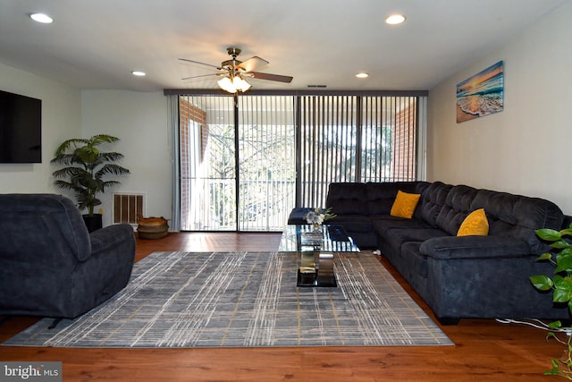 living room featuring ceiling fan, plenty of natural light, and dark wood-type flooring