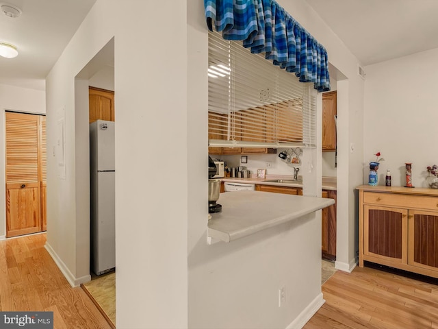 kitchen featuring white appliances, light hardwood / wood-style floors, and sink