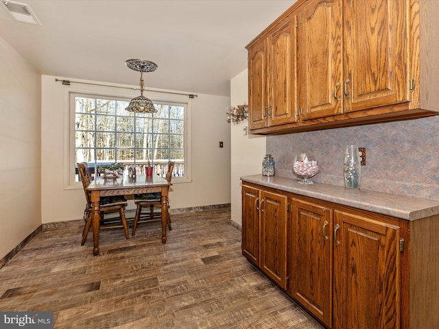 kitchen with backsplash, dark hardwood / wood-style flooring, and pendant lighting