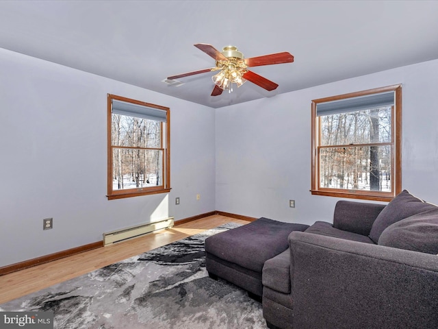 living room featuring hardwood / wood-style floors, ceiling fan, plenty of natural light, and a baseboard heating unit