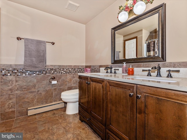 bathroom featuring vanity, toilet, baseboard heating, and tile walls