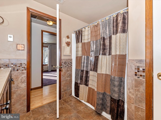 bathroom with a shower with curtain, tile patterned flooring, vanity, and tile walls