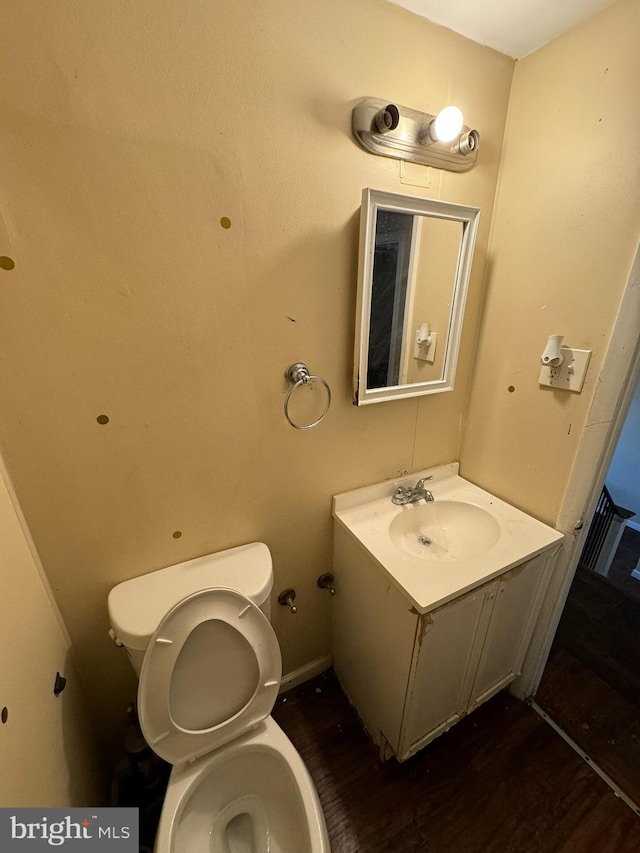 bathroom with wood-type flooring, vanity, and toilet