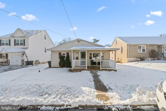 snow covered back of property featuring a garage and covered porch