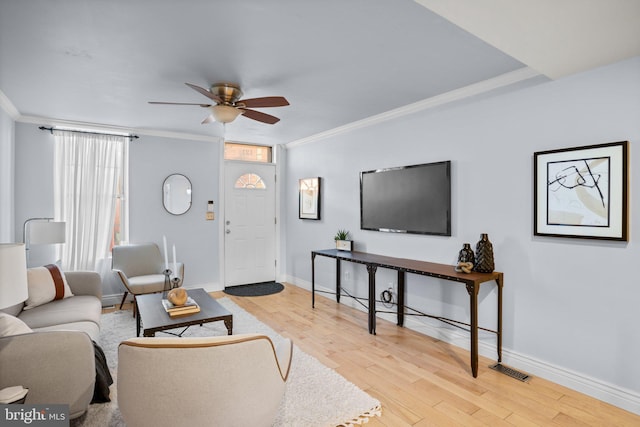 living room with light wood-type flooring, ceiling fan, and crown molding