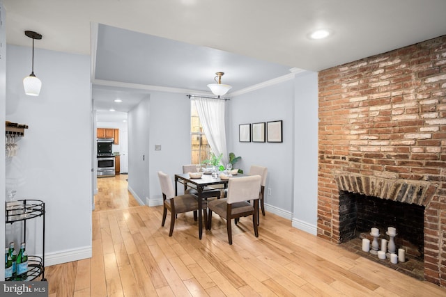 dining area with a brick fireplace, crown molding, and wood-type flooring