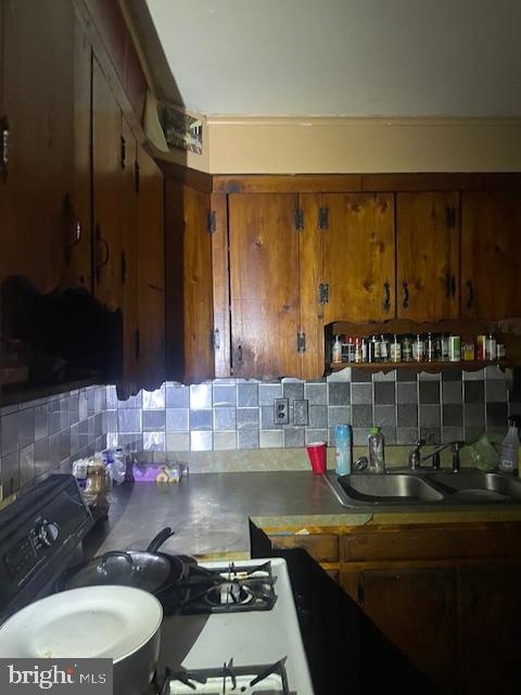 kitchen featuring black range with gas stovetop, sink, and tasteful backsplash